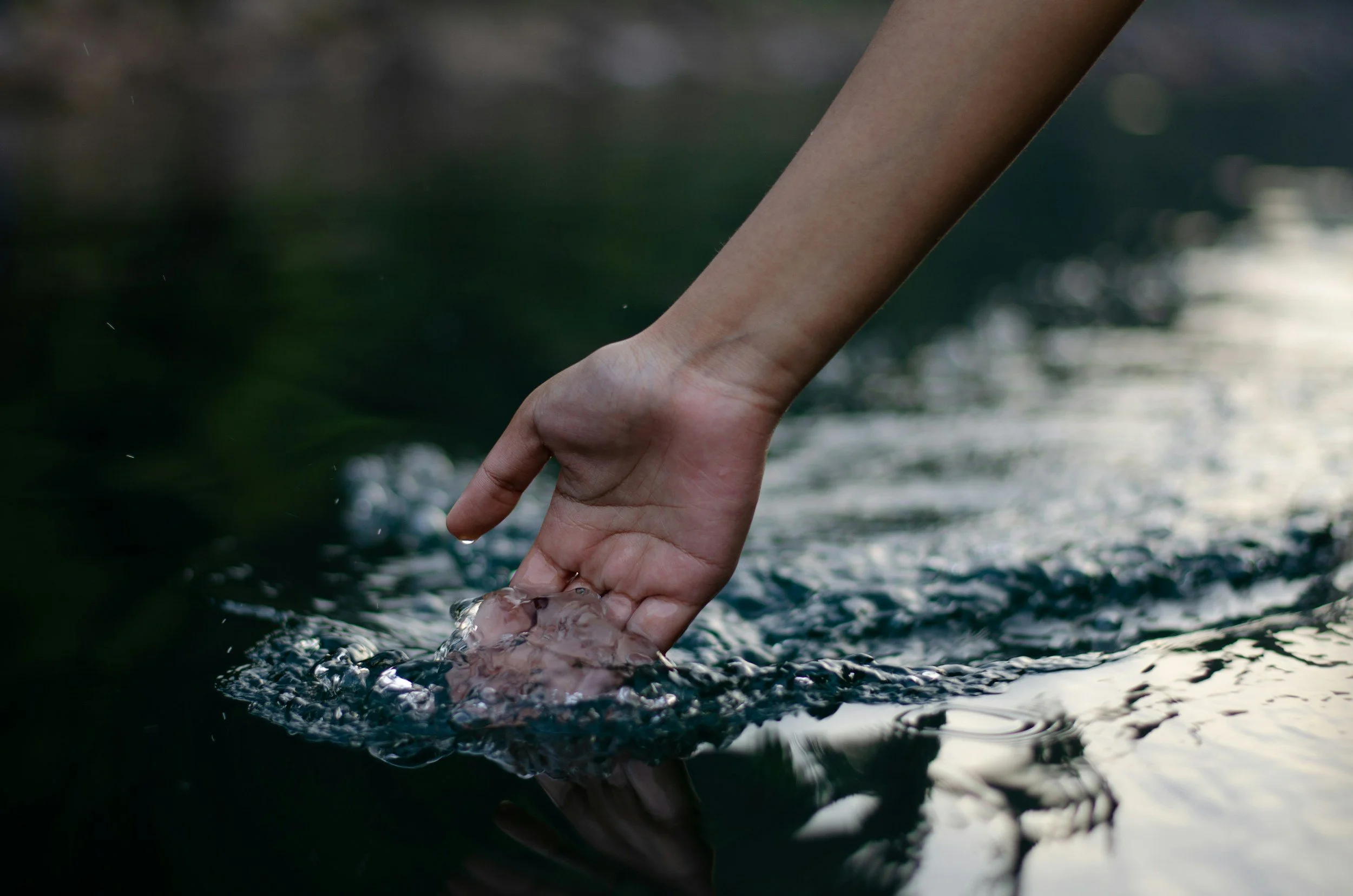 A hand touching flowing water